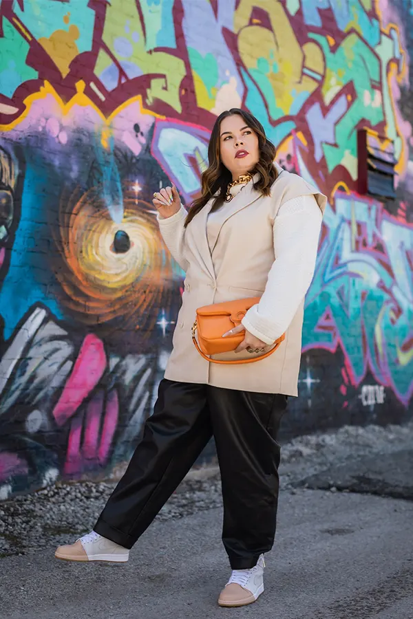 Cream Jacket With Black Pants And Orange Accent Bag