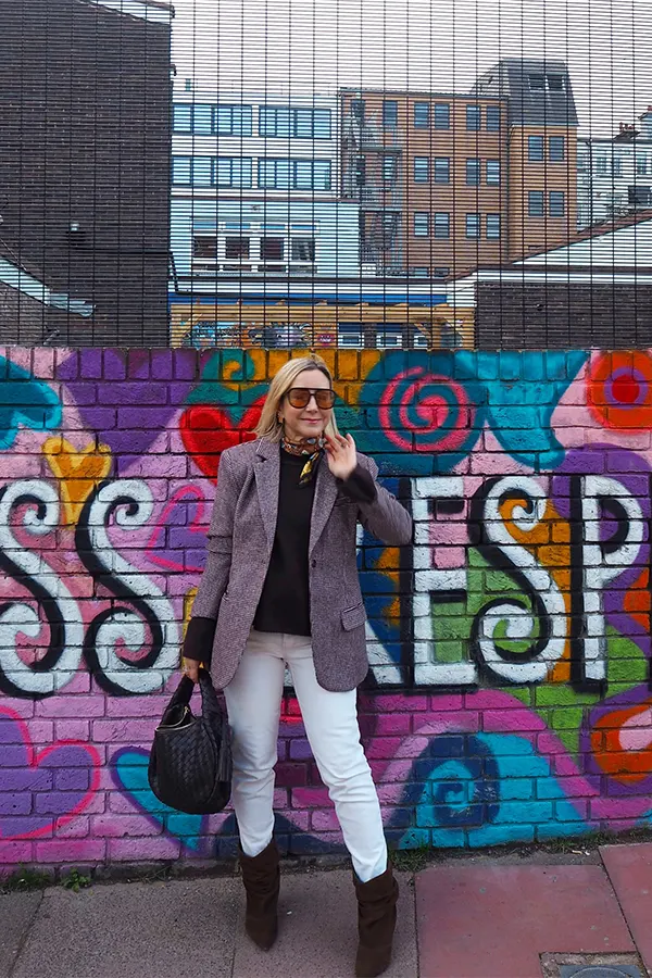 Dark Blazer White Trousers And Sneakers Against A Colorful Wall