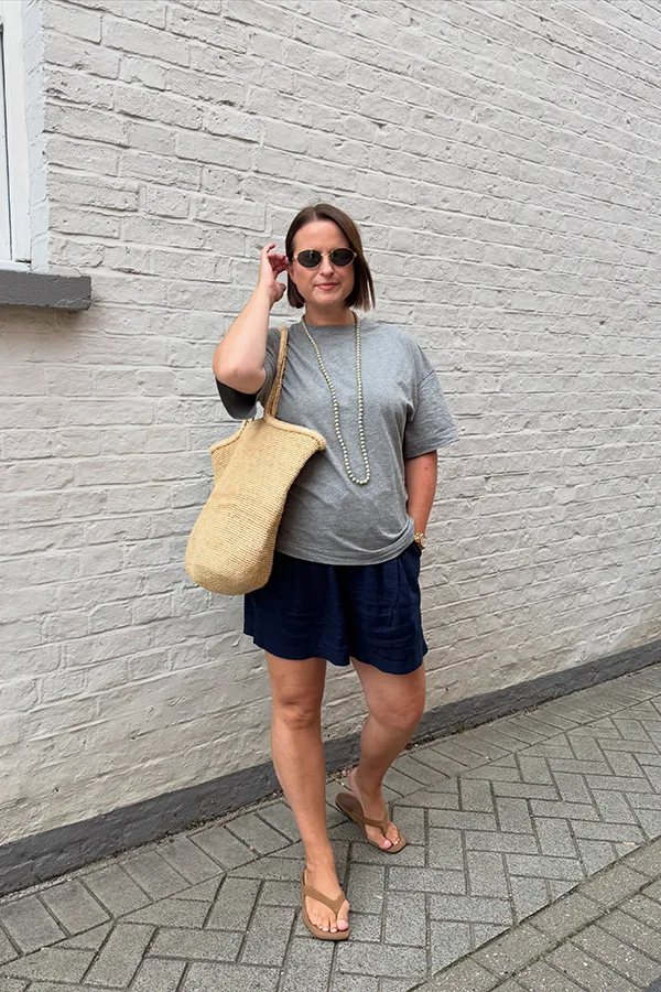 Gray Tee And Navy Shorts With A Straw Bag