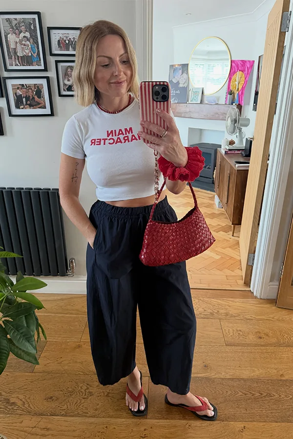 White Crop Top With Wide Leg Trousers And A Red Bag